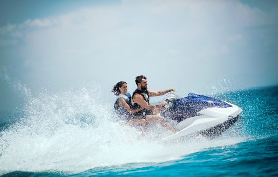 Young couple jet skiing on the open sea. They are smiling and enjoying summer sport on water.